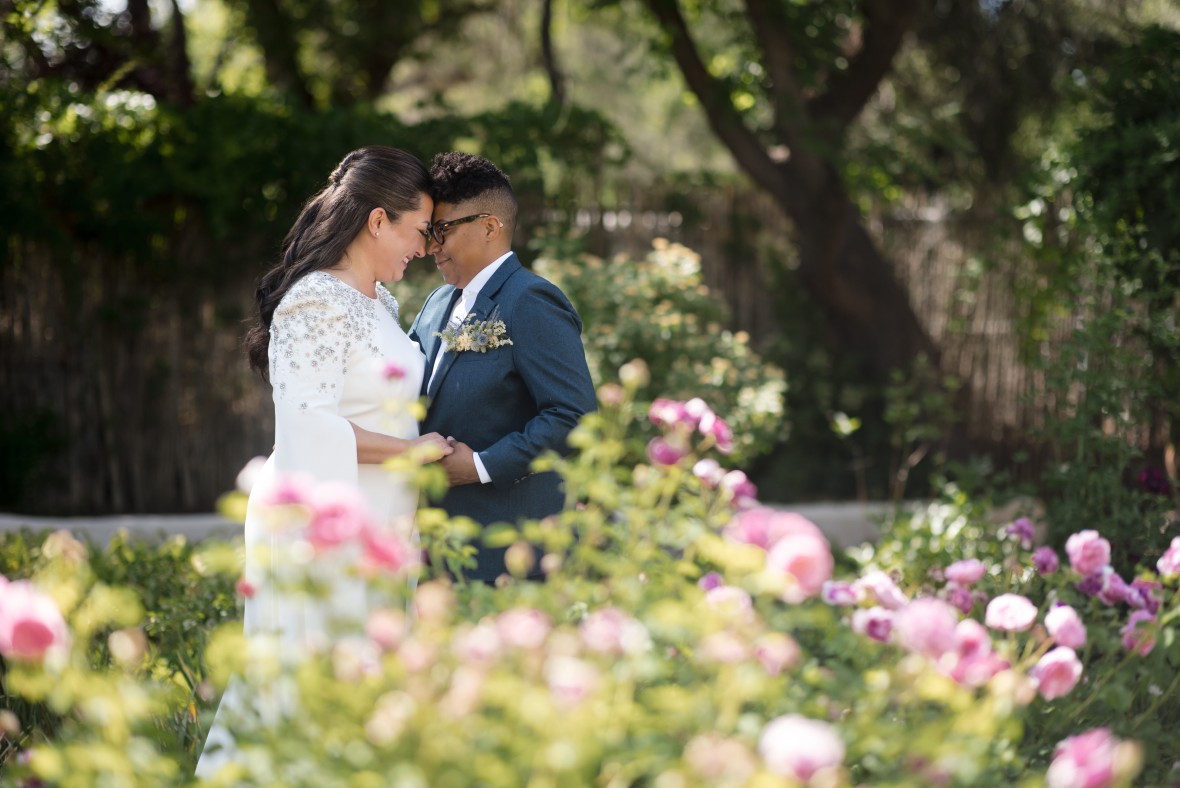 Couple embraces behind roses in bloom