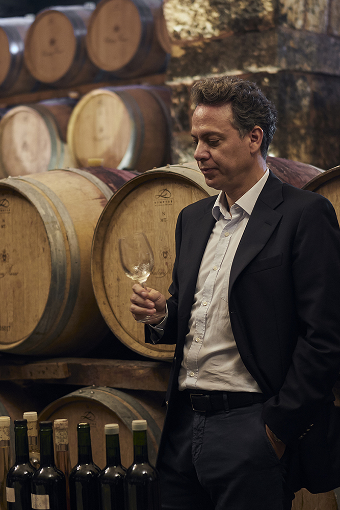 Marc Hochar from Château Musar stands in front of wine barrels 